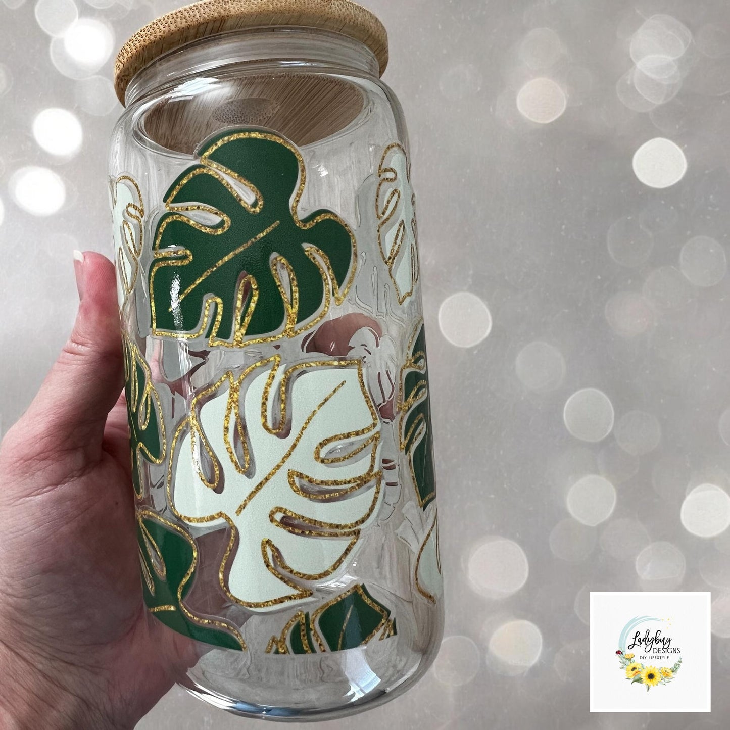 Monstera Leaf Cup with bamboo lid and plastic straw. Features a 16 oz beer can glass design with permanent UV DTF transfer. Perfect for iced coffee and plant lovers. Ideal as a plant mom gift, with hand wash care instructions.