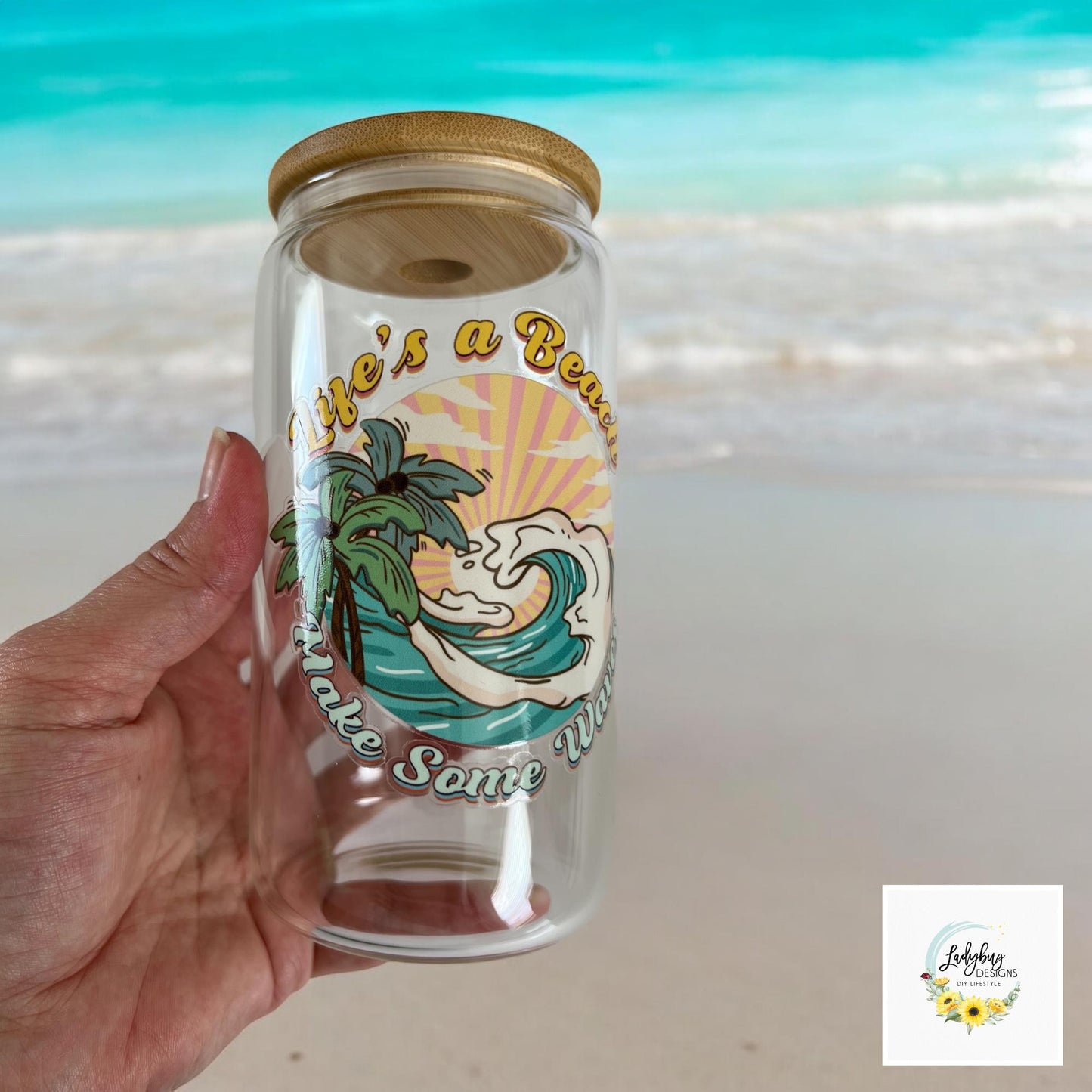 Life&#39;s a Beach Make Some Waves Cup with bamboo lid and plastic straw. Features a 16 oz beer can glass design with permanent UV DTF transfer. Perfect for iced coffee and summer vibes. Ideal as a funny and sarcastic gift, hand wash care instructions.