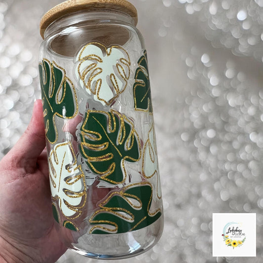 Monstera Leaf Cup with bamboo lid and plastic straw. Features a 16 oz beer can glass design with permanent UV DTF transfer. Perfect for iced coffee and plant lovers. Ideal as a plant mom gift, with hand wash care instructions.